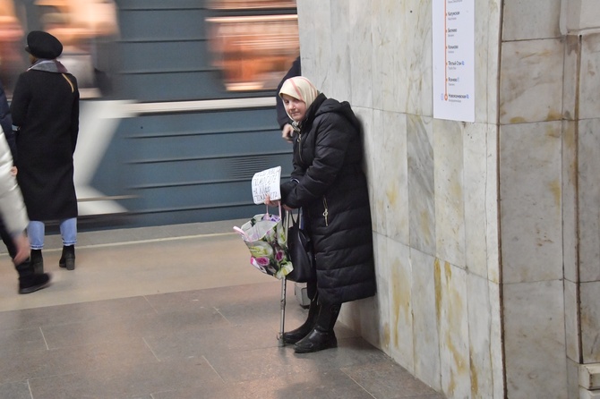 Пожилая женщина просит милостыню в метро