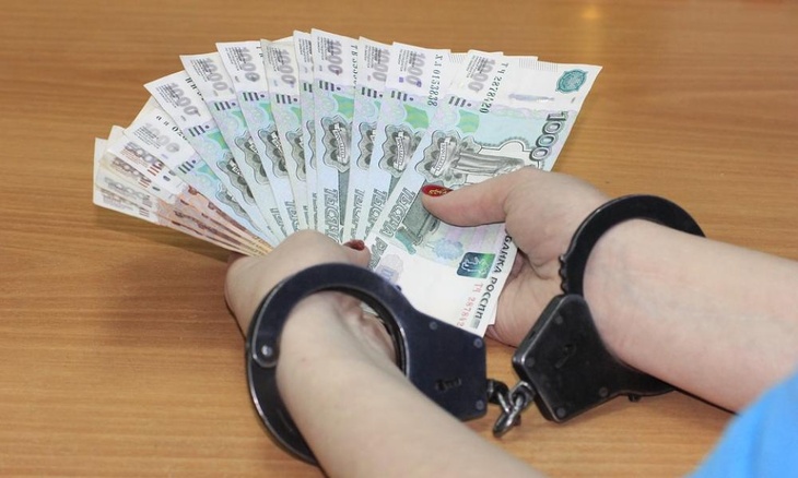 Руки в наручниках с деньгами