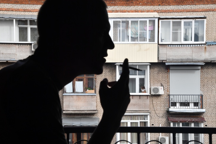 Человек курит на балконе