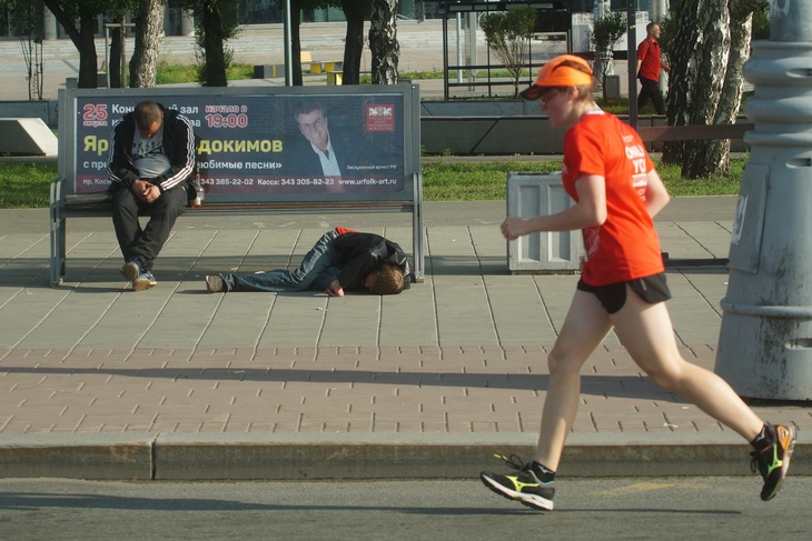 Участник забега бежит мимо остановки с пьяными мужчинами