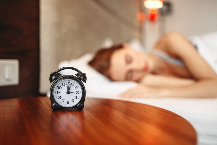 будильник на фоне спящей женщины