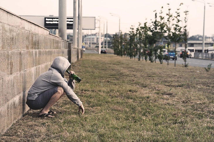 молодой человек сидит с бутылкой спиртного