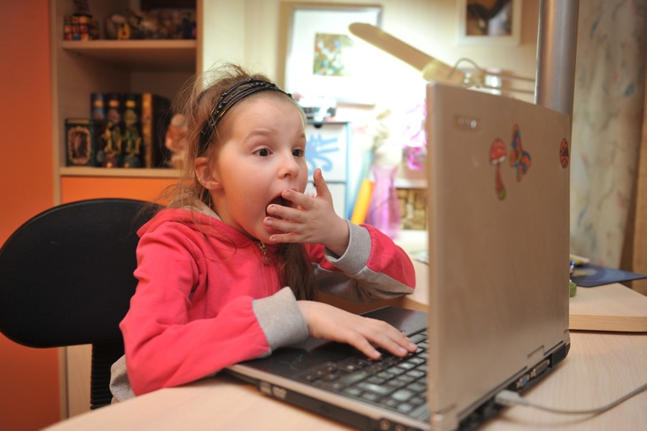 Девочка удивленно смотрит в компьютер.