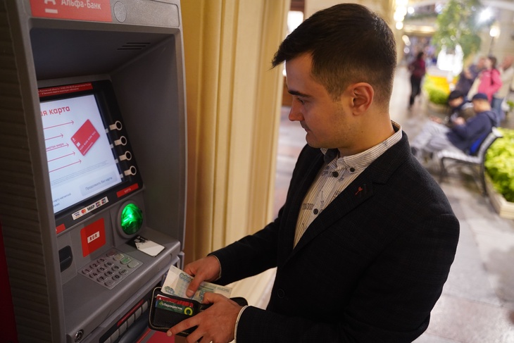 Мужчина снимает зарплату с банкомата