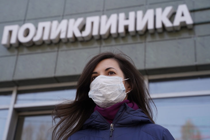 Девушка в медицинской маске у поликлиники Девушка в медицинской маске у поликлиники